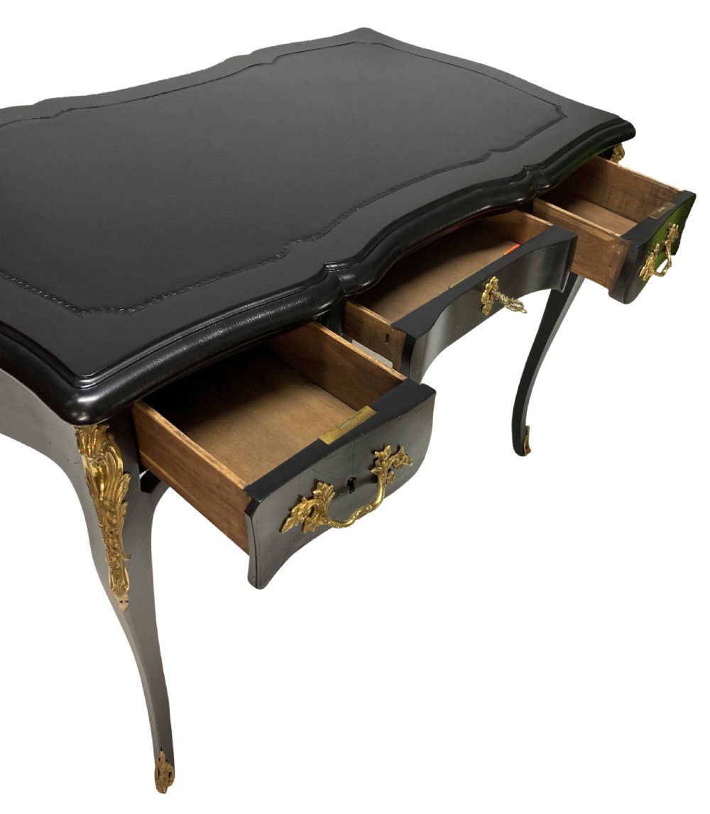 A Louis XV style black lacquered writing table with cabriole legs, an inset leather surface, and ornate gilt bronze corner mounts. View VI
