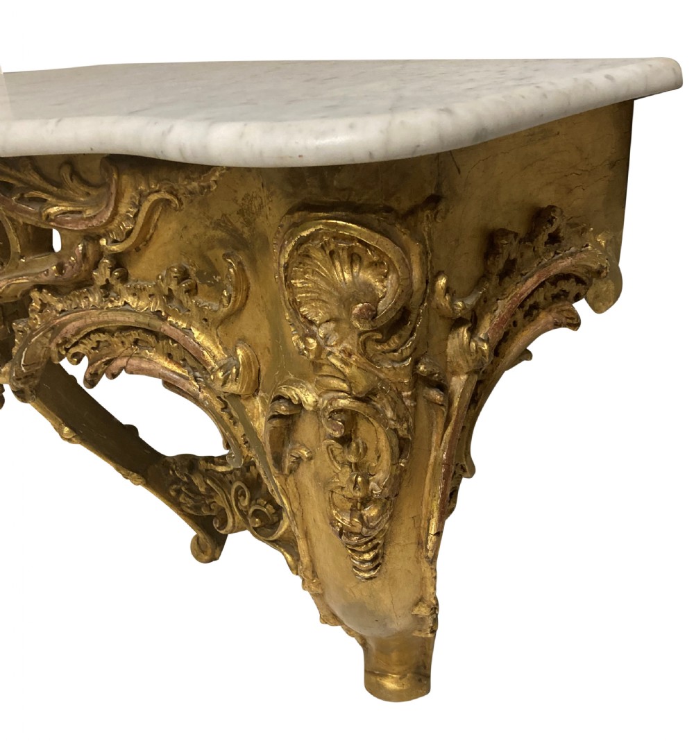 A 19th-century German Rococo Revival carved giltwood console table featuring an openwork scrolled apron and a serpentine white marble top. View III