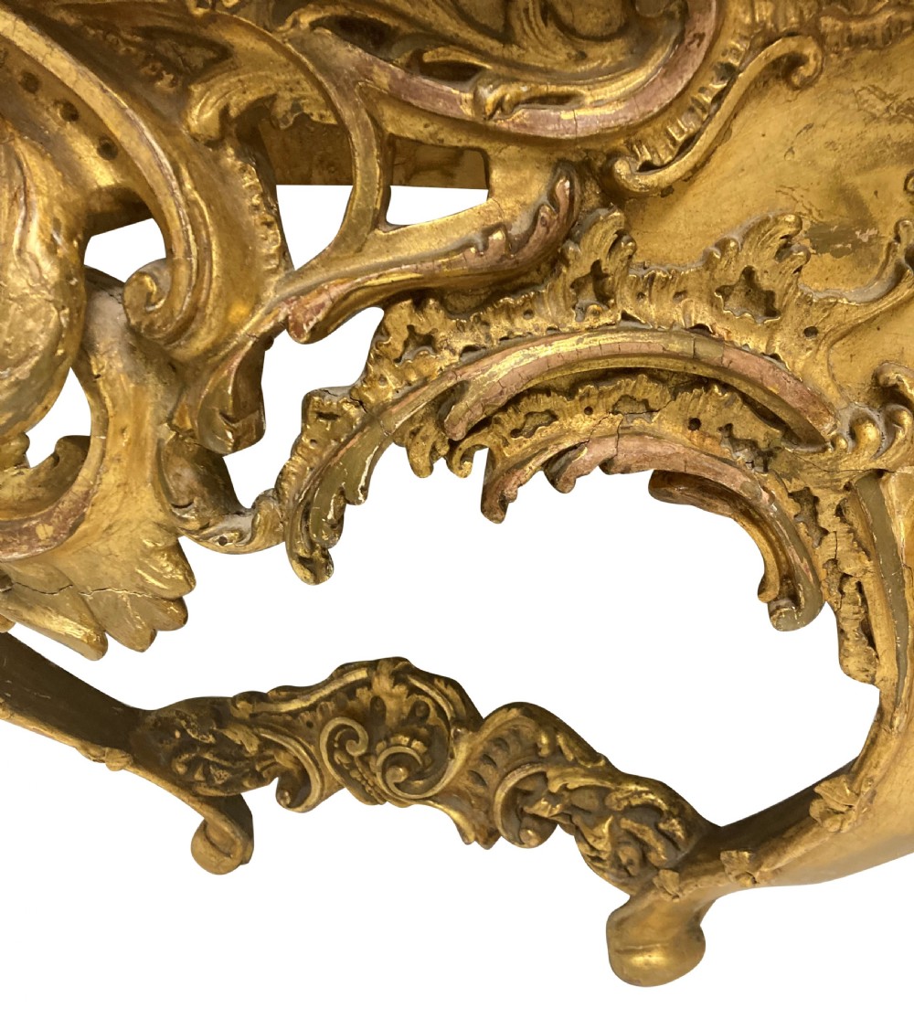 A 19th-century German Rococo Revival carved giltwood console table featuring an openwork scrolled apron and a serpentine white marble top. View IV