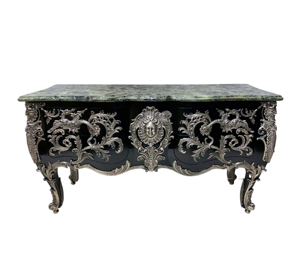 A French Rococo style black lacquered commode featuring a green marble top and elaborate silver-coloured ornamental mounts.