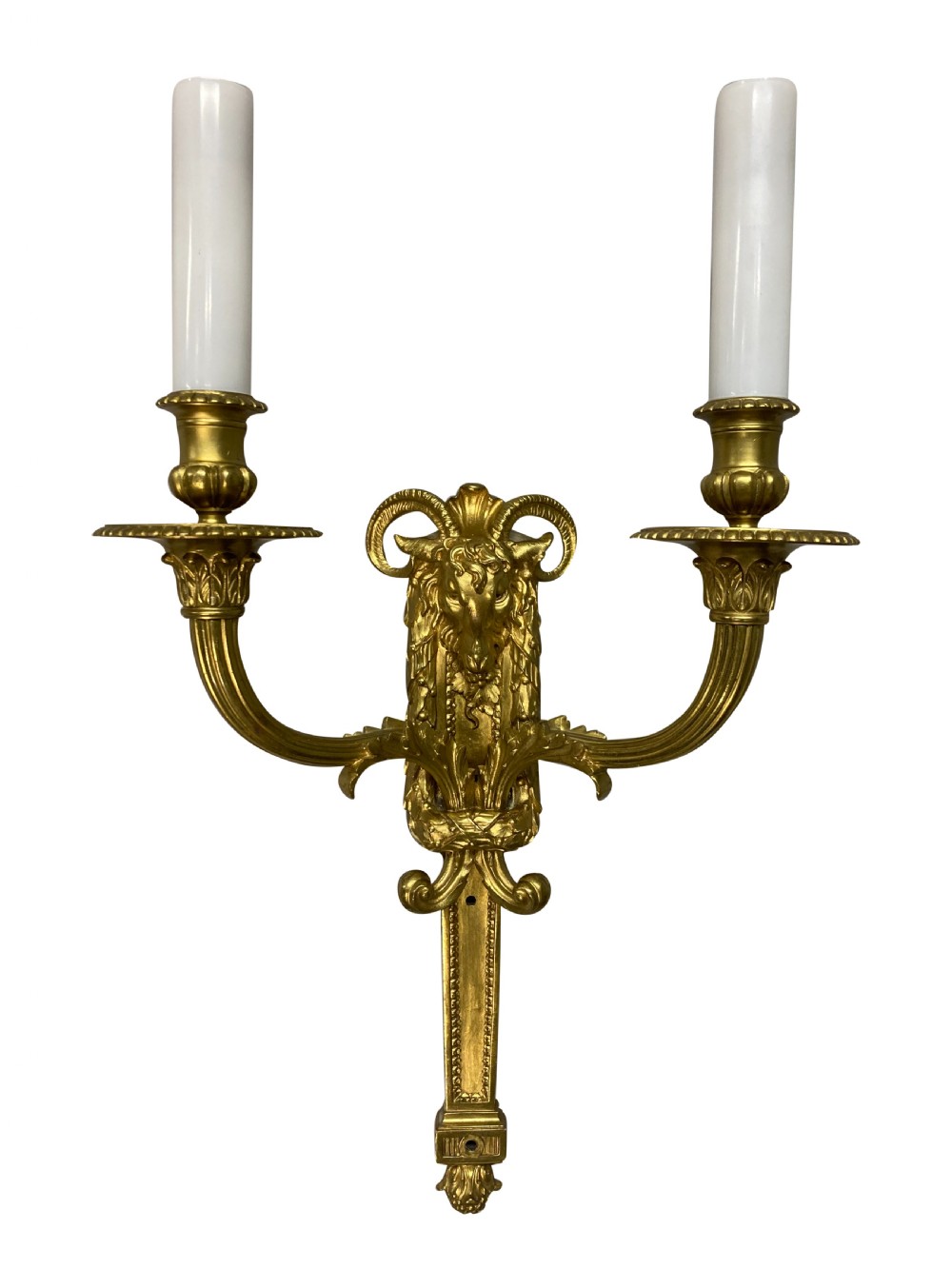 A pair of gilt brass Regency style twin-arm wall sconces featuring ram head central backplates and white candle sleeves. View II