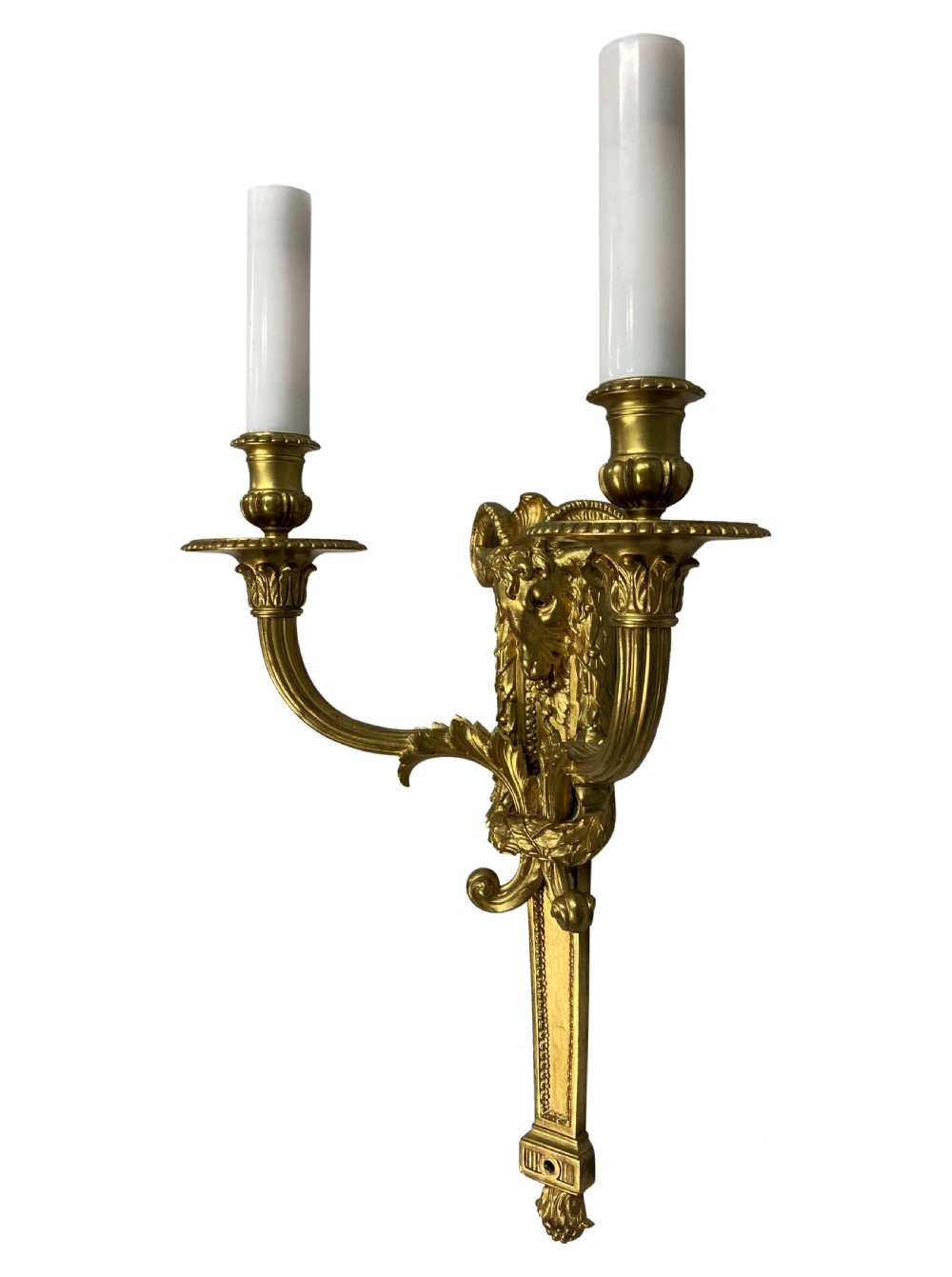 A pair of gilt brass Regency style twin-arm wall sconces featuring ram head central backplates and white candle sleeves. View III