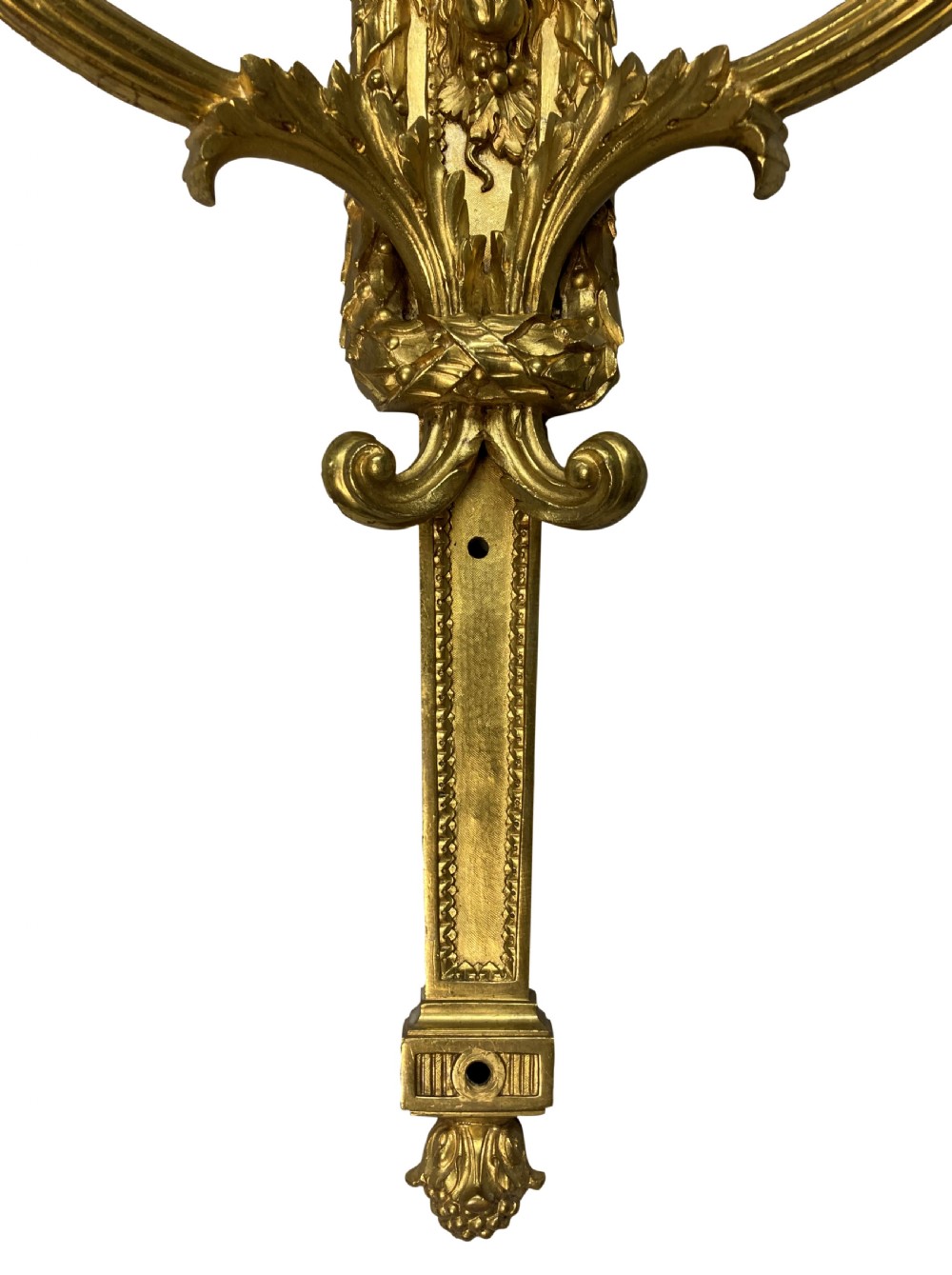 A pair of gilt brass Regency style twin-arm wall sconces featuring ram head central backplates and white candle sleeves. View IV