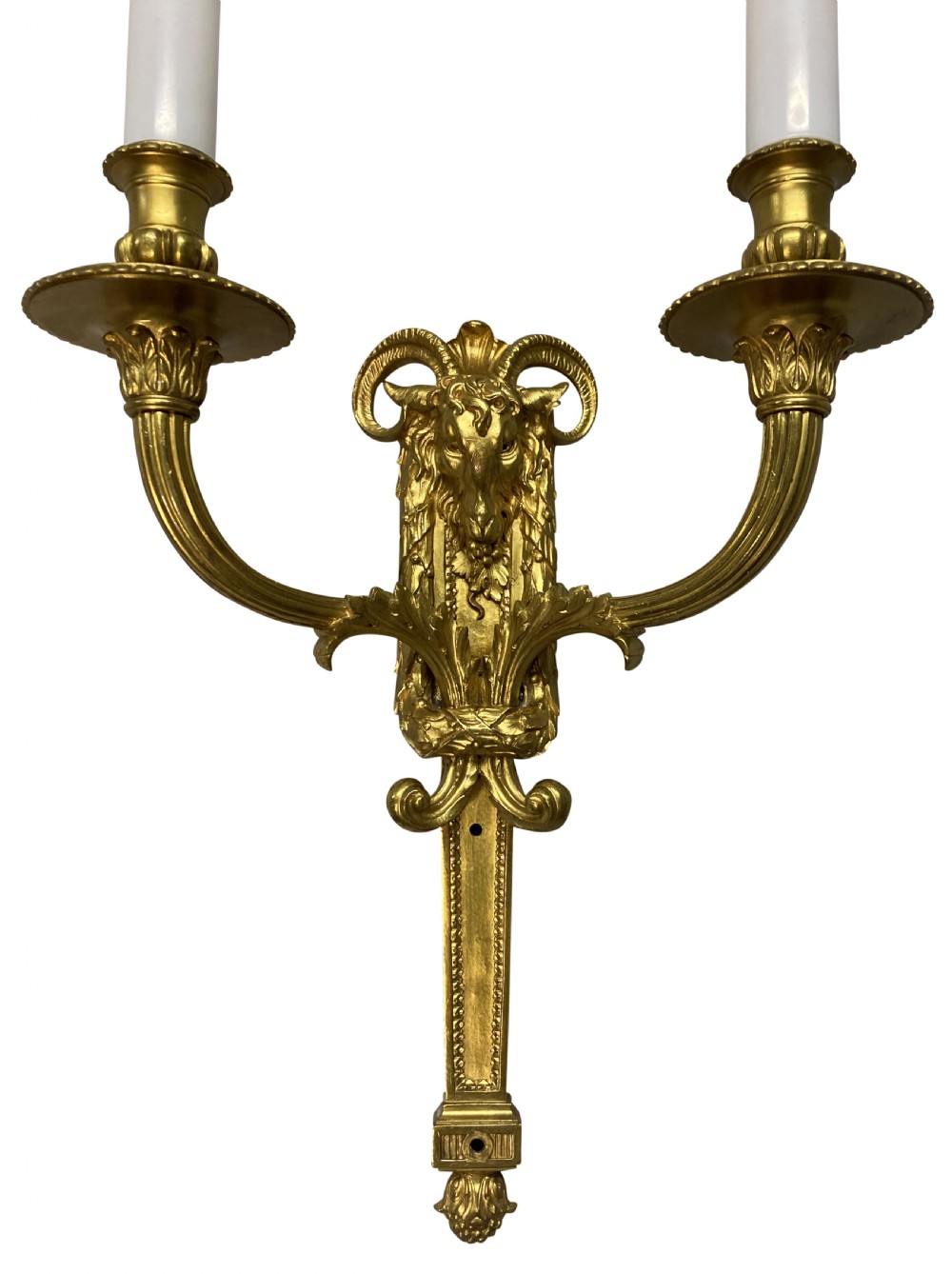 A pair of gilt brass Regency style twin-arm wall sconces featuring ram head central backplates and white candle sleeves. View VI