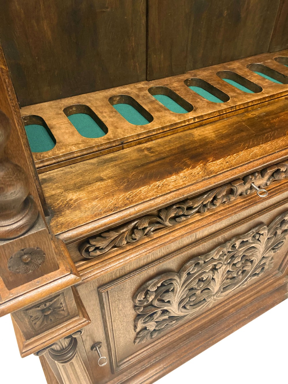 A nineteenth-century carved oak gun cabinet featuring spiralled barley twist columns, a glazed upper door, and relief-carved botanical motifs on the lower door. View III