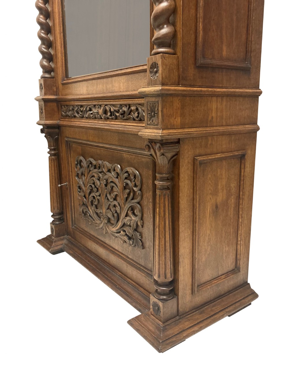 A nineteenth-century carved oak gun cabinet featuring spiralled barley twist columns, a glazed upper door, and relief-carved botanical motifs on the lower door. View V