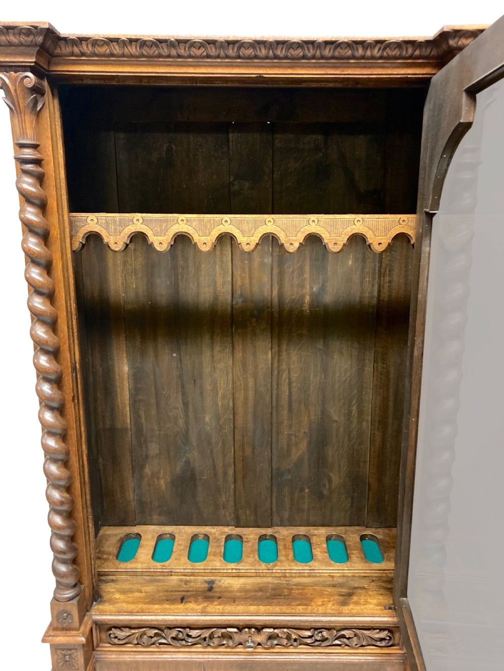A nineteenth-century carved oak gun cabinet featuring spiralled barley twist columns, a glazed upper door, and relief-carved botanical motifs on the lower door. View VIII