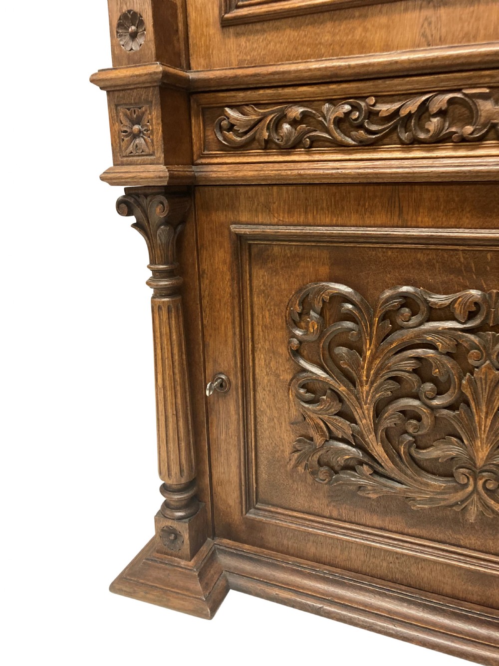 A nineteenth-century carved oak gun cabinet featuring spiralled barley twist columns, a glazed upper door, and relief-carved botanical motifs on the lower door. View XII