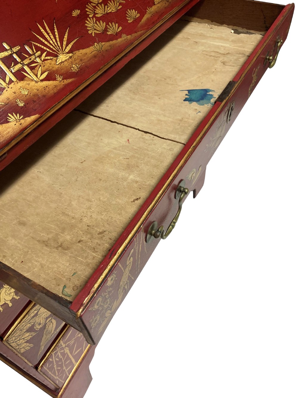 A George III scarlet japanned writing bureau featuring gilded Chinoiserie imagery, a slant front, and four long drawers on bracket feet. View II