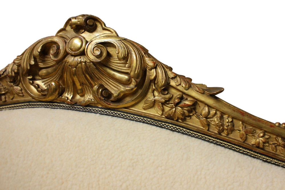 An early nineteenth-century giltwood settee featuring a carved cresting rail, cabriole legs, and cream upholstery. View V