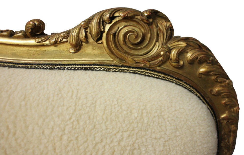 An early nineteenth-century giltwood settee featuring a carved cresting rail, cabriole legs, and cream upholstery. View VI