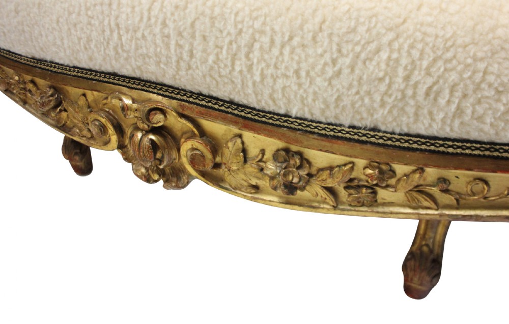 An early nineteenth-century giltwood settee featuring a carved cresting rail, cabriole legs, and cream upholstery. View VII