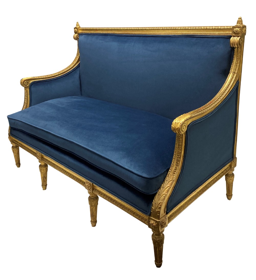 A French Louis XVI style settee featuring a carved giltwood frame with tapered fluted legs and blue velvet cushion upholstery. View II