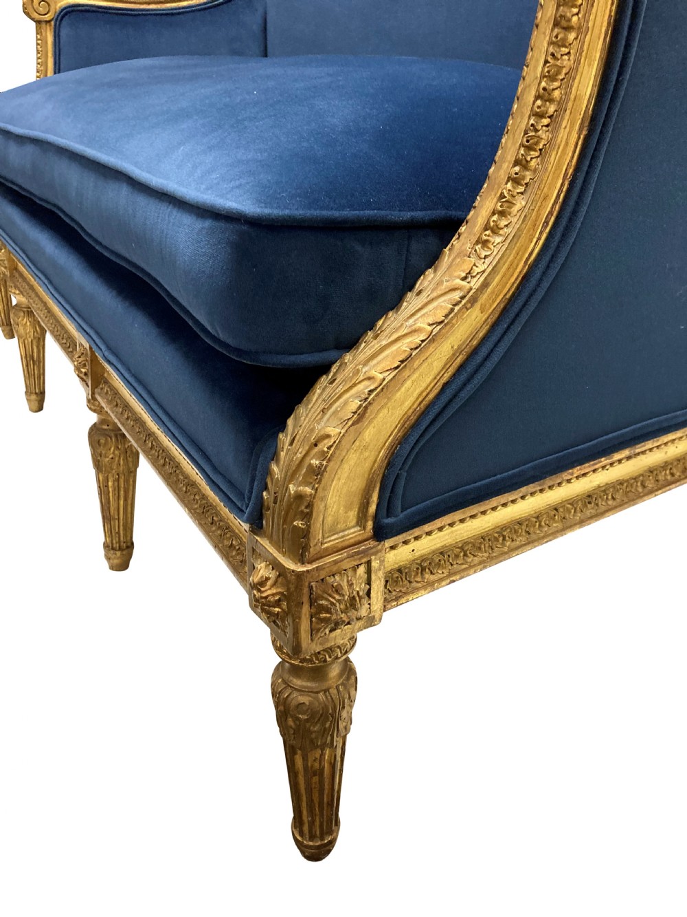 A French Louis XVI style settee featuring a carved giltwood frame with tapered fluted legs and blue velvet cushion upholstery. View V