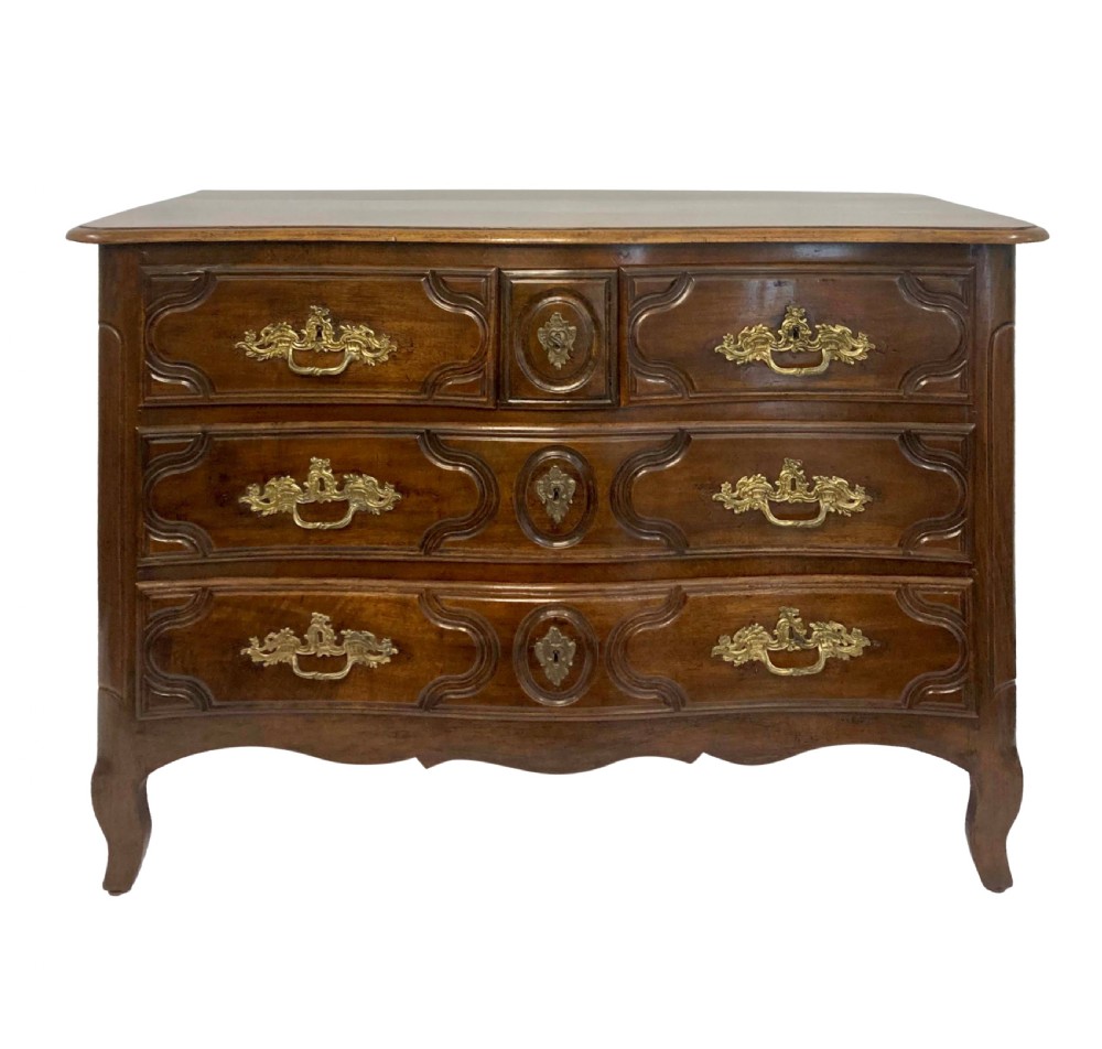 A French provincial walnut commode featuring three carved drawers with rococo brass handles and short cabriole legs.