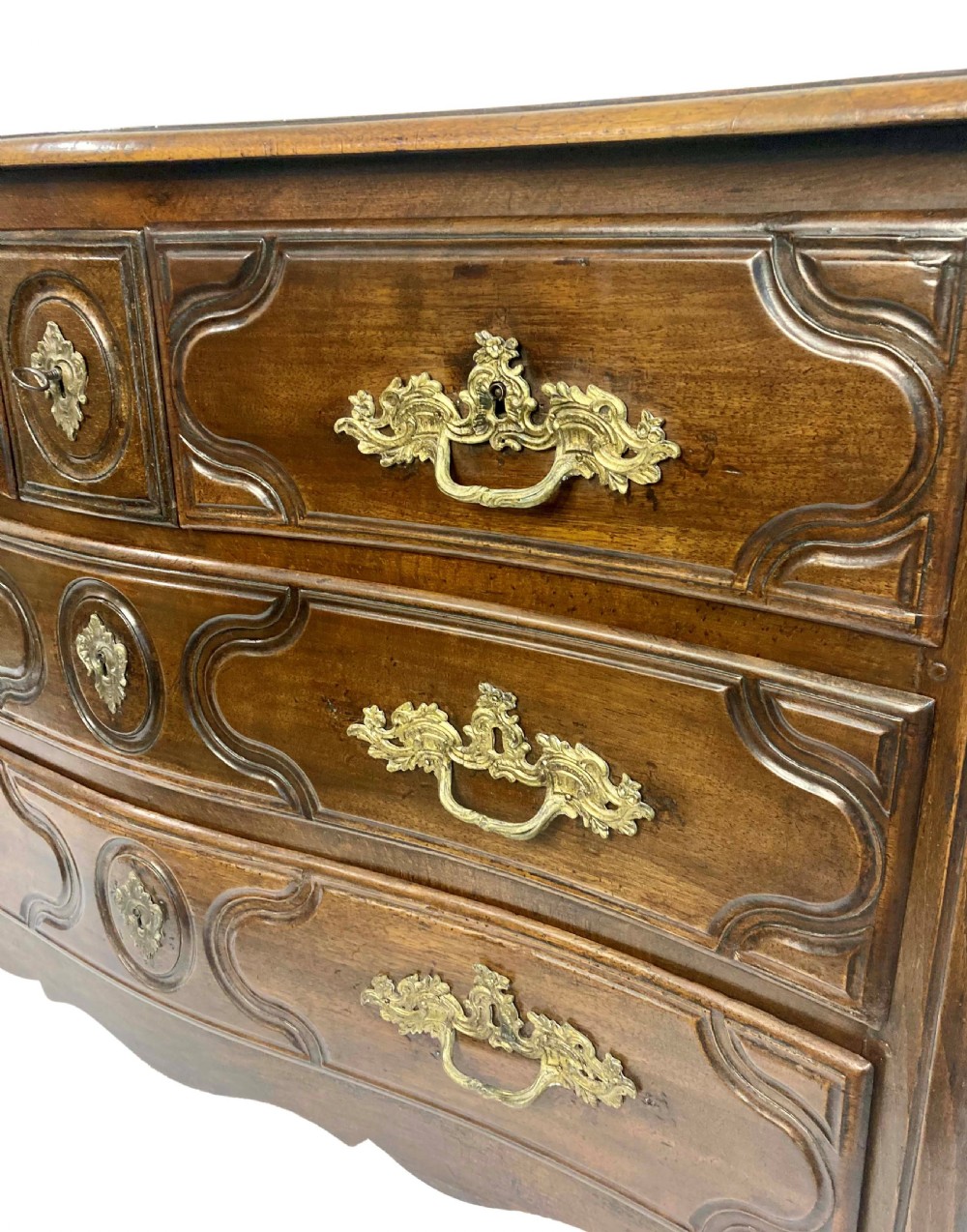 A French provincial walnut commode featuring three carved drawers with rococo brass handles and short cabriole legs. View III