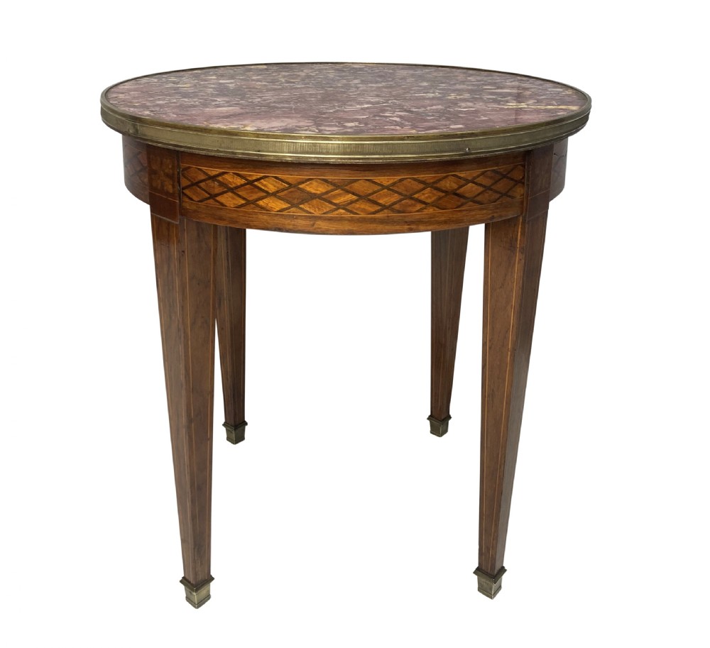 A nineteenth-century French circular gueridon table with a mottled marble top, brass rim, diamond parquetry frieze, and tapered legs.