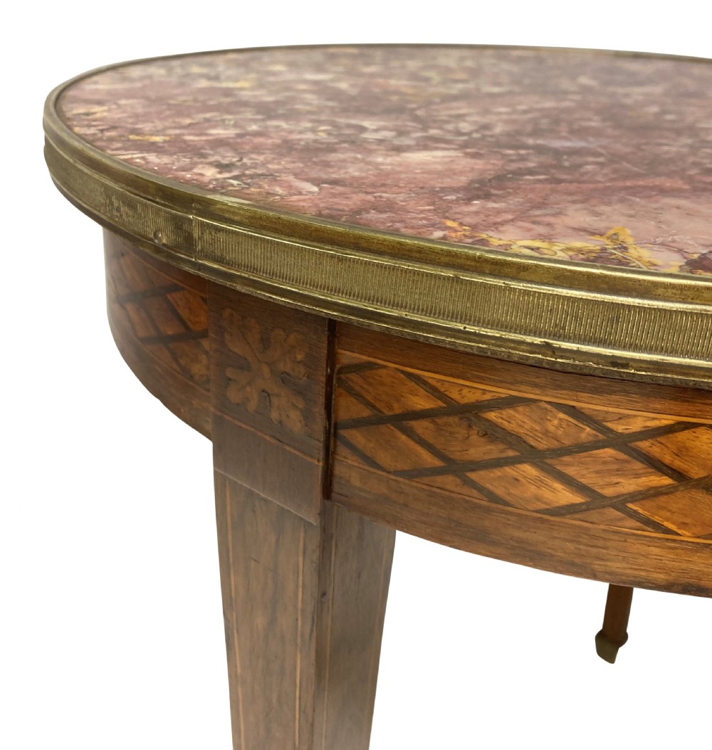A nineteenth-century French circular gueridon table with a mottled marble top, brass rim, diamond parquetry frieze, and tapered legs. View VI