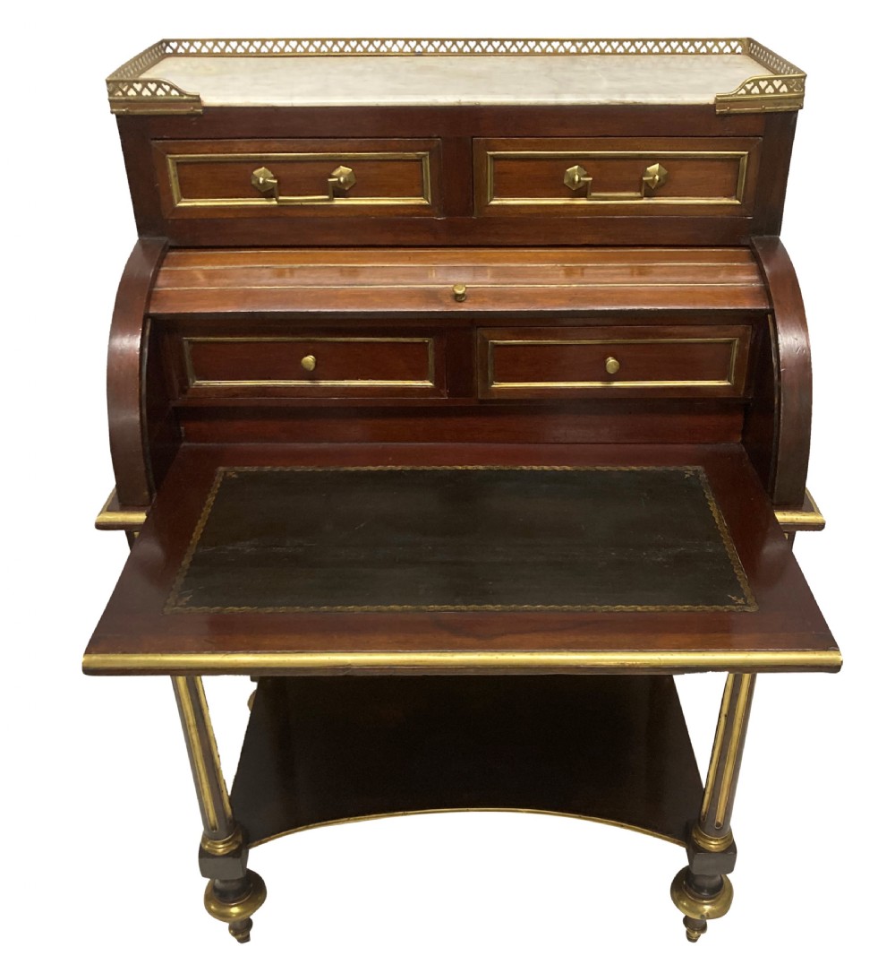 A small Directoire style mahogany cylinder desk with brass inlay trim, a marble top framed by a pierced brass gallery, slatted roll-top cylinder, drawer, and tapered legs. View VI