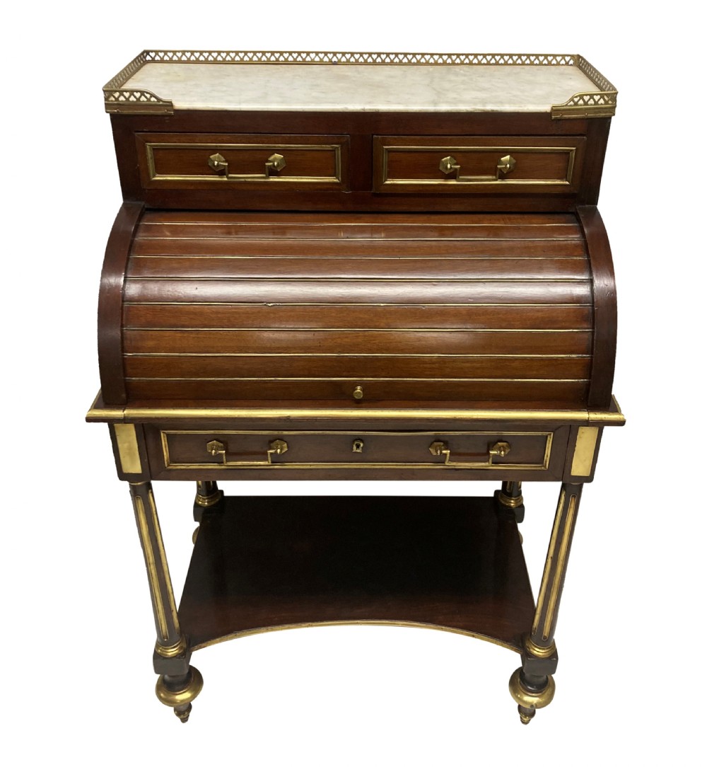 A small Directoire style mahogany cylinder desk with brass inlay trim, a marble top framed by a pierced brass gallery, slatted roll-top cylinder, drawer, and tapered legs. View IX
