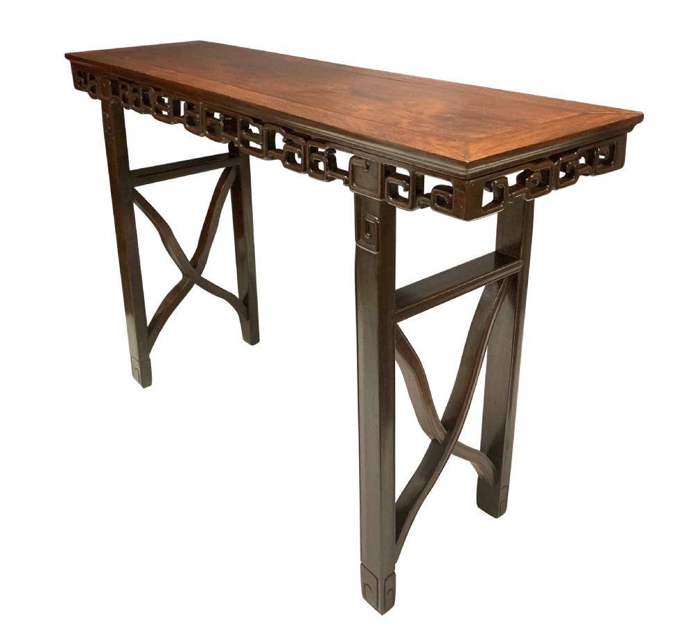 A dark brown Chinese Qing dynasty console table featuring an openwork geometric fretwork apron and curved side stretchers.