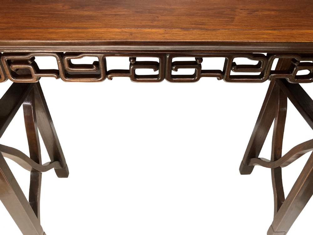 A dark brown Chinese Qing dynasty console table featuring an openwork geometric fretwork apron and curved side stretchers. View V