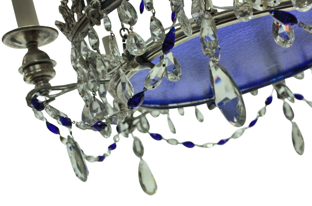 A 19th-century silver-plated circular chandelier featuring clear and cobalt blue cut glass drops, candle sleeves, and a central cobalt glass insert suspended by chains. View VI