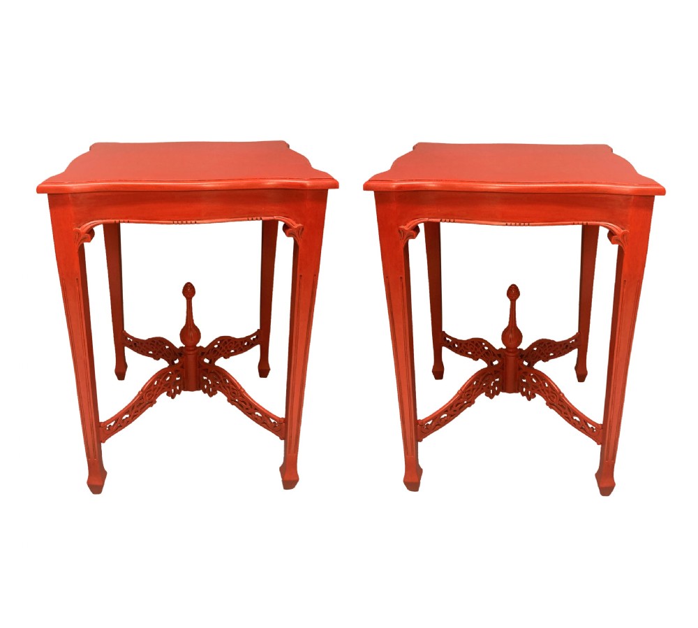 A pair of scarlet red square side tables featuring serpentine tops, carved corner brackets, and intricate pierced X-stretchers with central finials.