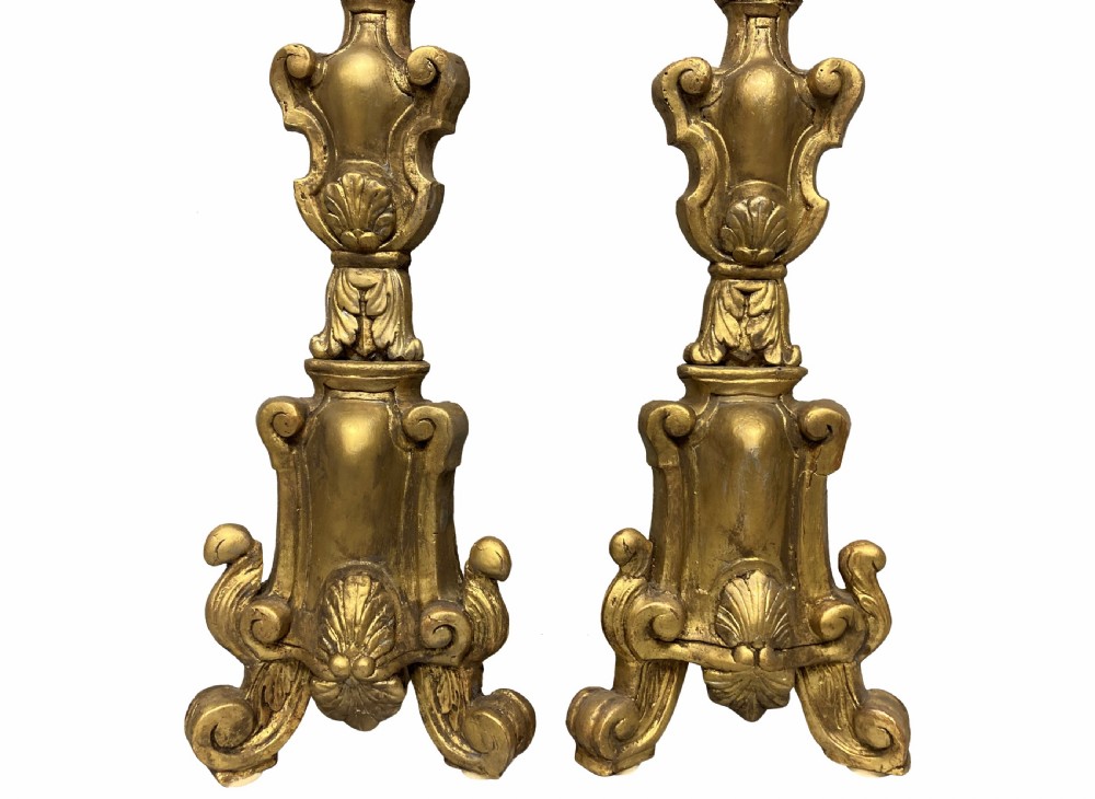 A pair of tall 18th-century Italian carved giltwood table lamps featuring scroll bases, shell carvings, and cream faux candle stems. View II