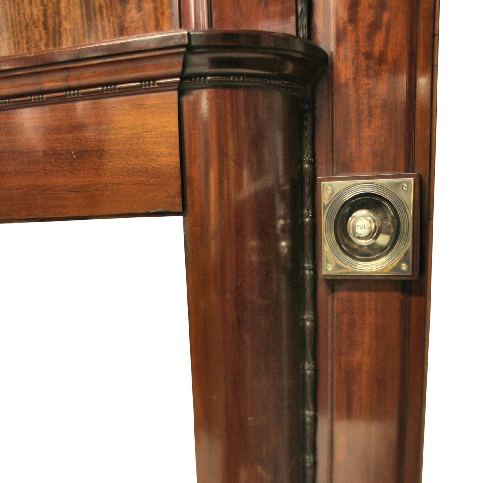 A large dark polished mahogany chimneypiece featuring an integrated panelled overmantel and architectural stepped mouldings. View IX