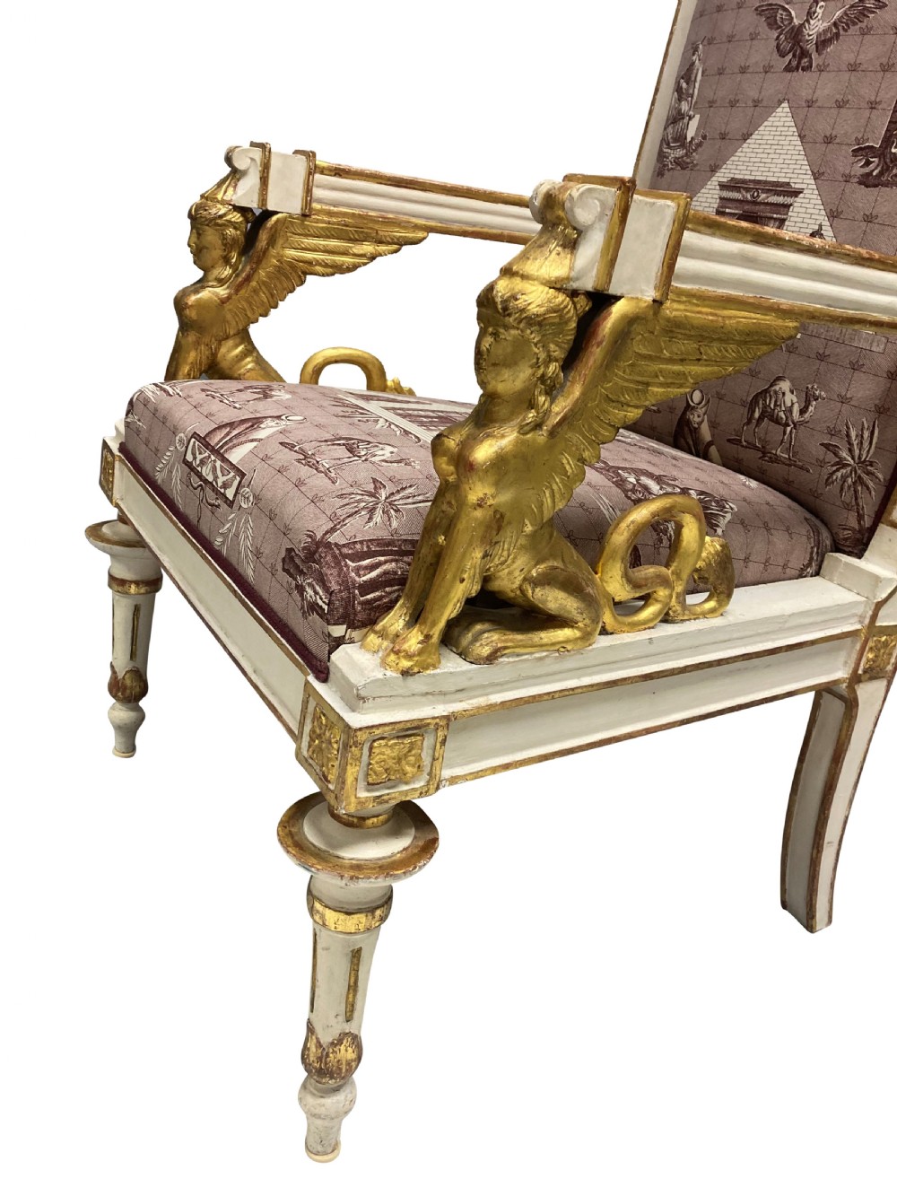 A French Empire armchair featuring a white painted frame with gilt sphinx arm supports and Egyptian revival fabric upholstery. View V