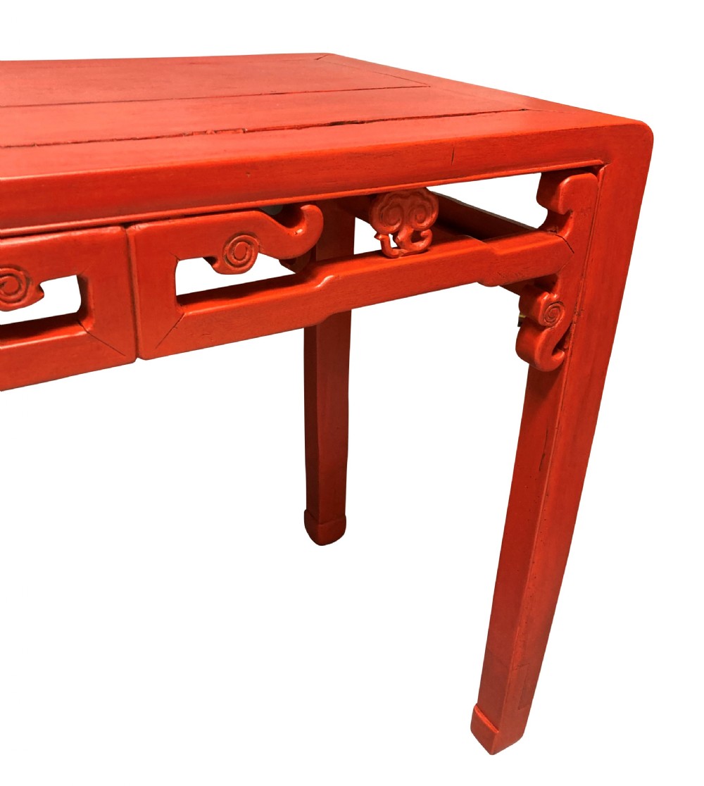 A 19th-century Chinese red lacquered console table featuring a long rectangular top and carved scroll aprons along the frame. View III