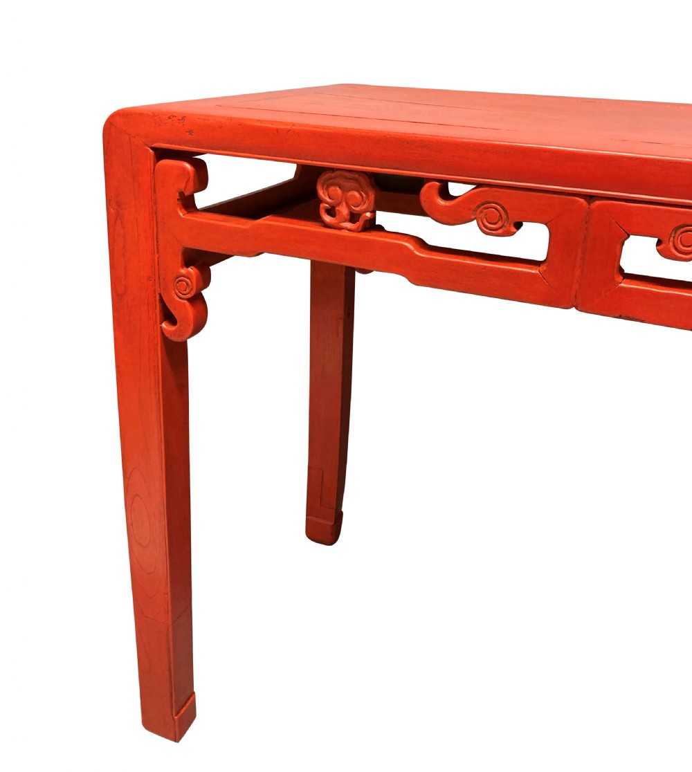A 19th-century Chinese red lacquered console table featuring a long rectangular top and carved scroll aprons along the frame. View IV