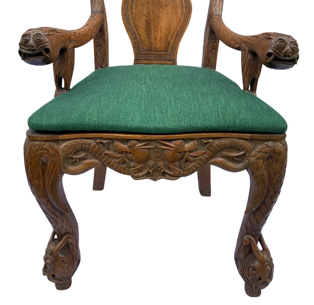 A pair of 19th-century carved teak Chinese armchairs featuring dragon motif armrests, detailed back splats, cabriole legs, and green upholstered seat cushions. View X