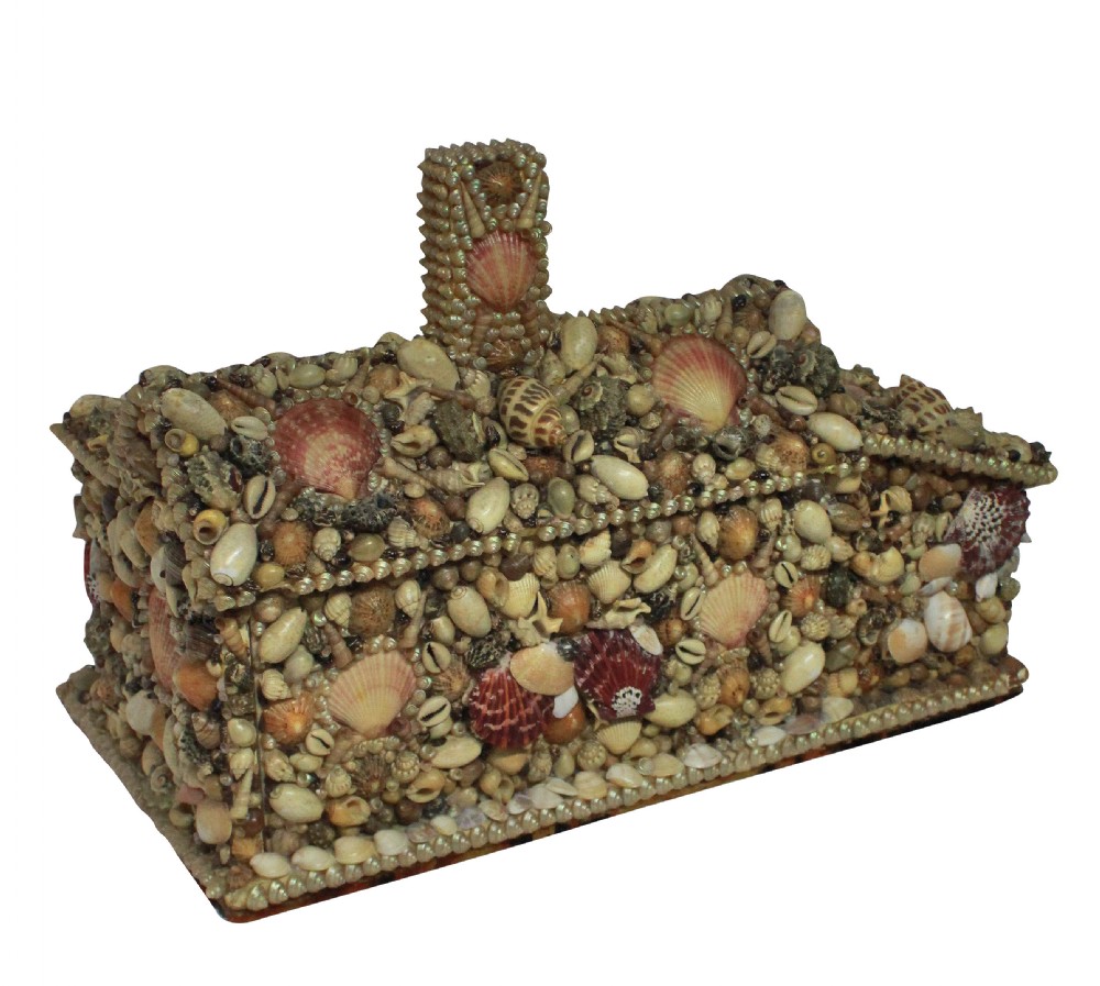 A miniature cottage-shaped decorative object encrusted with various small natural seashells and featuring a central open recess and a shell-covered chimney. View III