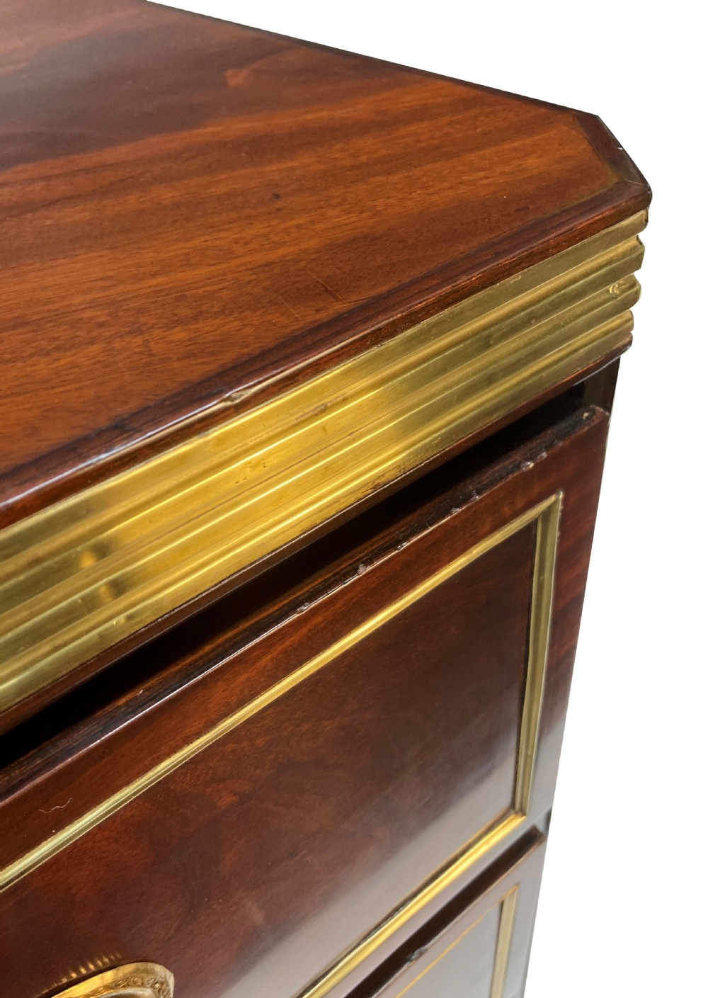An early nineteenth-century Russian mahogany commode with three drawers decorated with brass inlay borders, circular brass handles, central escutcheons, and fluted brass side pilasters. View VIII