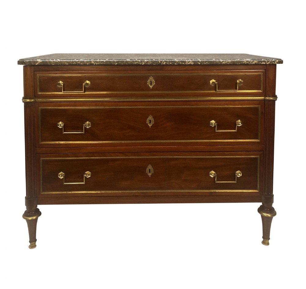 A French Directoire mahogany commode featuring three long drawers with brass mounts, fluted corner pilasters, and a grey marble top.