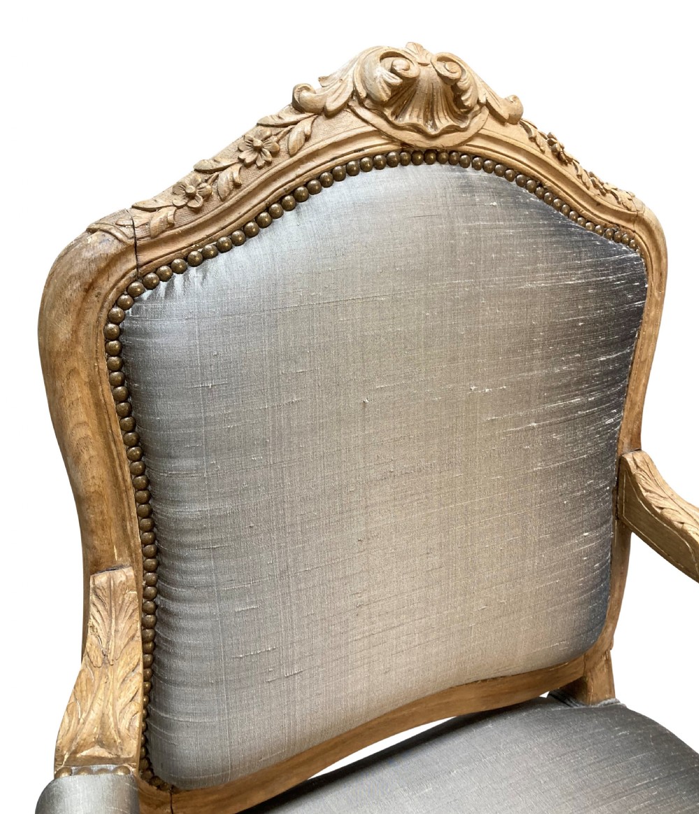 A Louis XV style armchair featuring a carved bleached fruitwood frame with cabriole legs and grey silk upholstery secured with brass studs. View III