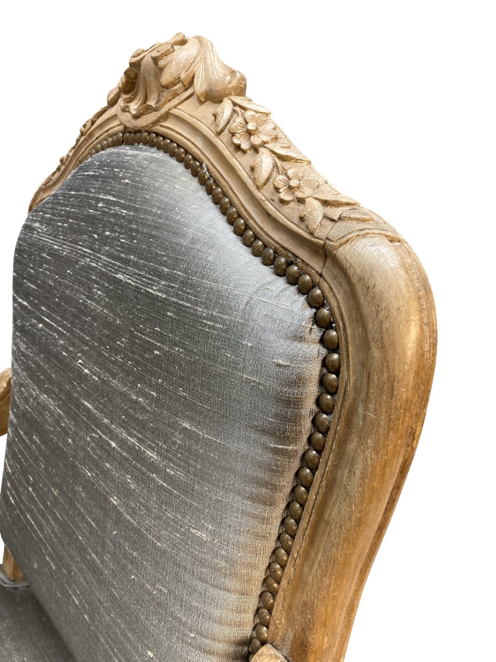 A Louis XV style armchair featuring a carved bleached fruitwood frame with cabriole legs and grey silk upholstery secured with brass studs. View IV