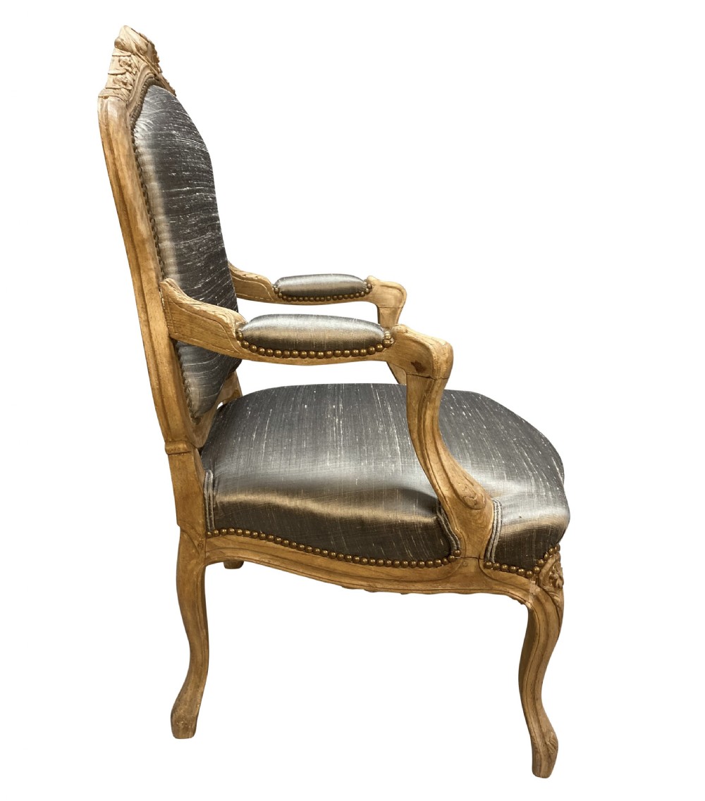 A Louis XV style armchair featuring a carved bleached fruitwood frame with cabriole legs and grey silk upholstery secured with brass studs. View V