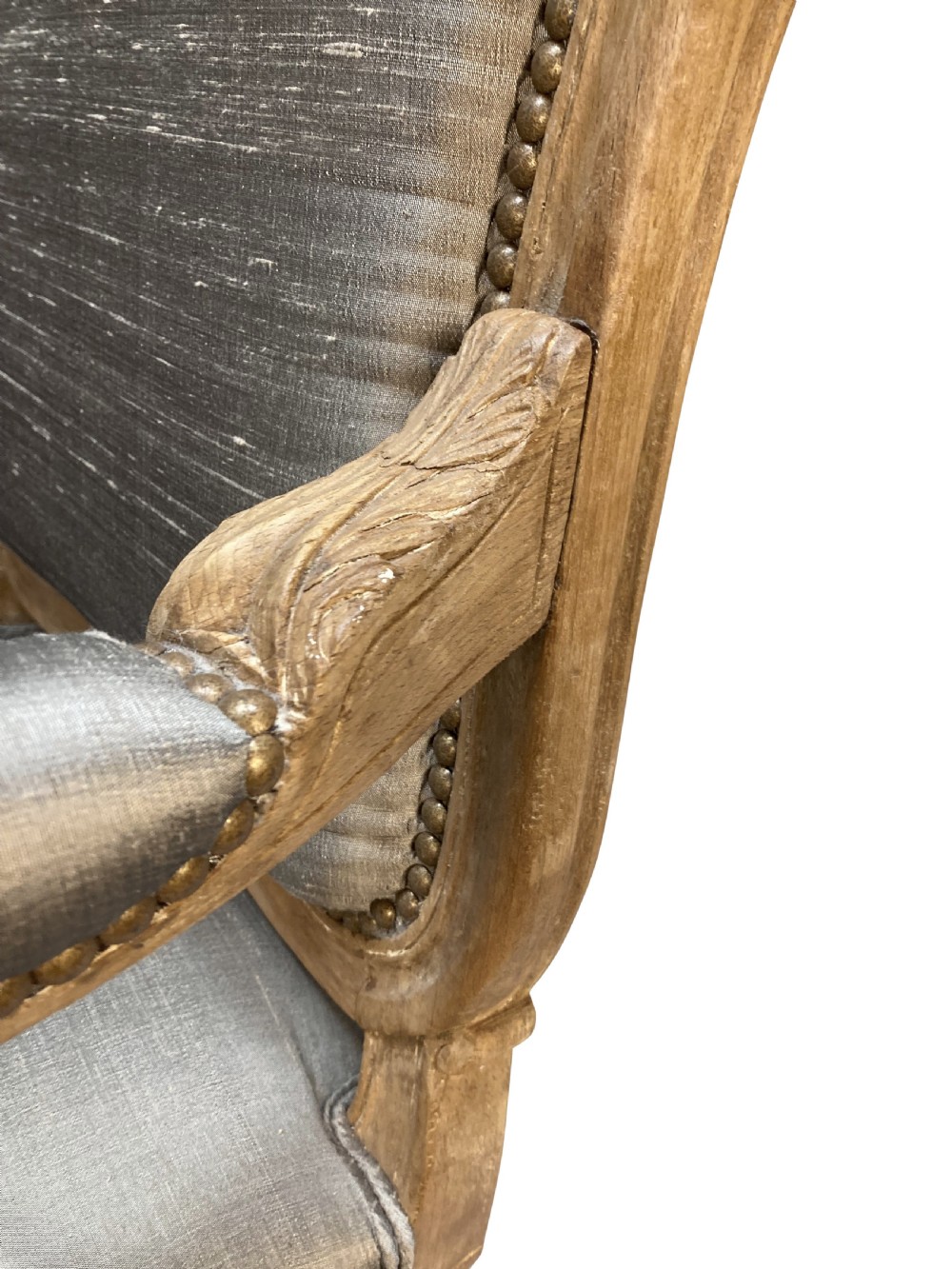 A Louis XV style armchair featuring a carved bleached fruitwood frame with cabriole legs and grey silk upholstery secured with brass studs. View VIII