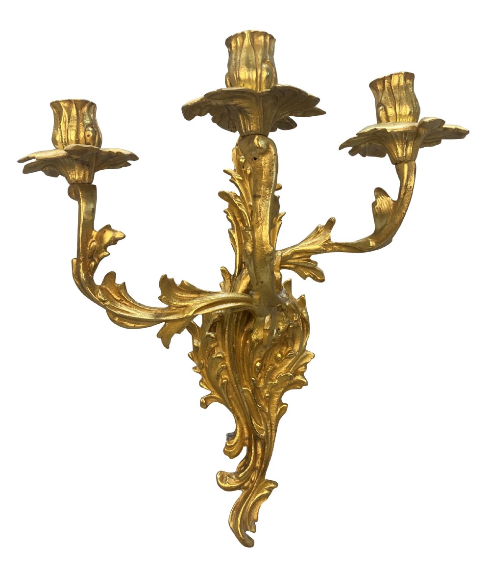 A pair of Louis XV style gilt bronze three-arm wall sconces featuring scrolling foliage motifs and leaf-shaped drip pans. View II