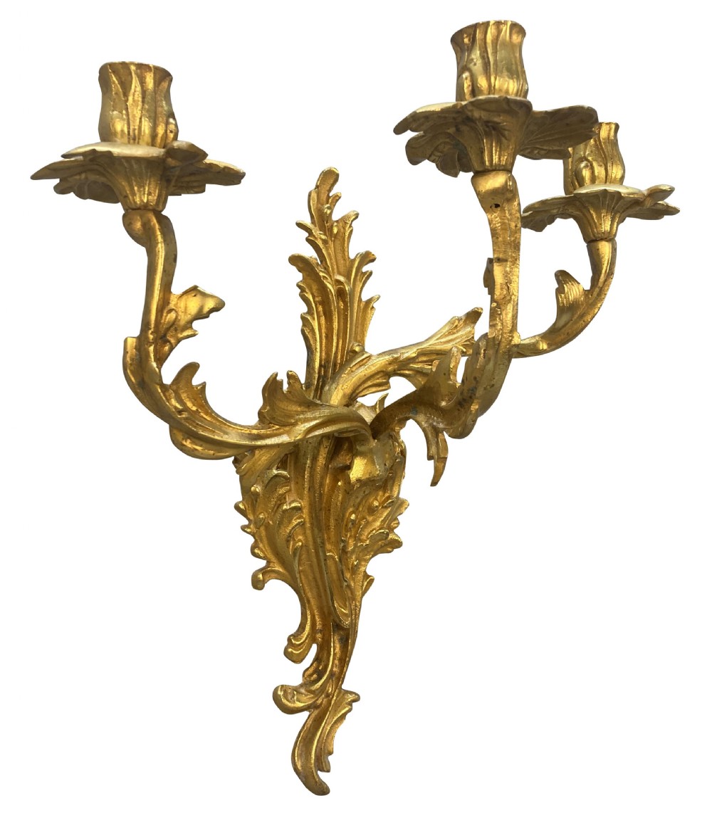 A pair of Louis XV style gilt bronze three-arm wall sconces featuring scrolling foliage motifs and leaf-shaped drip pans. View III