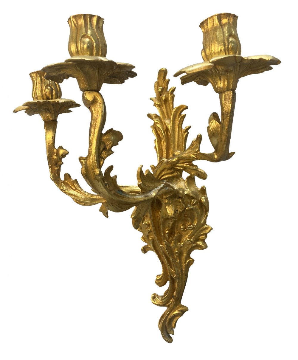 A pair of Louis XV style gilt bronze three-arm wall sconces featuring scrolling foliage motifs and leaf-shaped drip pans. View IV