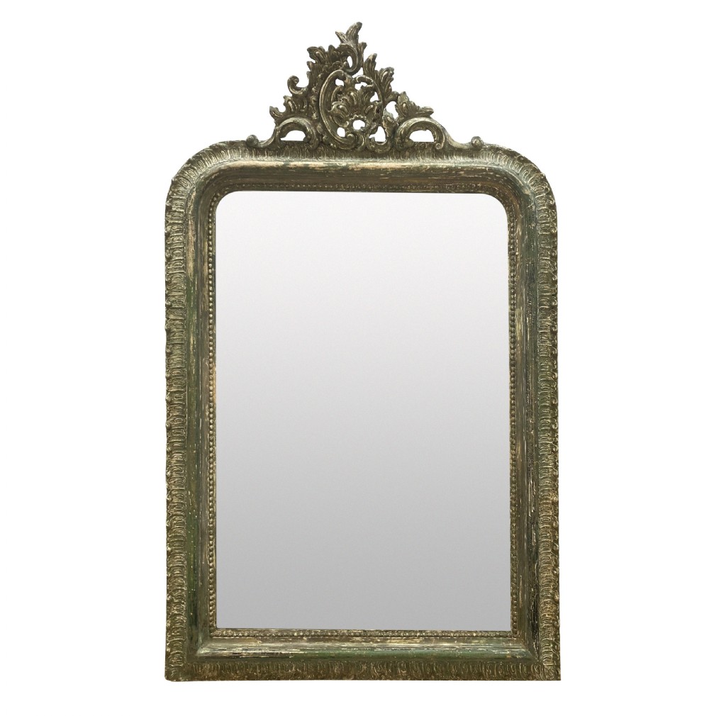 An arched Louis XV style rectangular overmantel mirror featuring a carved ornate scroll crest and a weathered green and gilded frame.