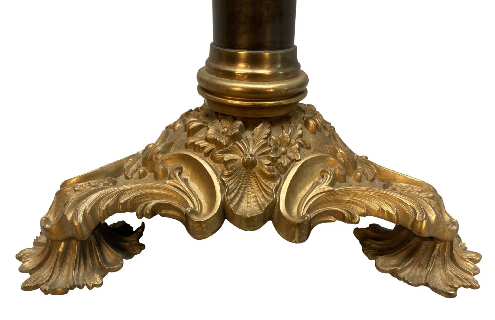 An English table lamp base featuring a dark patinated bronze cylindrical column mounted on a gilt ormolu triform base with scrolled feet and topped with an acanthus leaf capital. View II