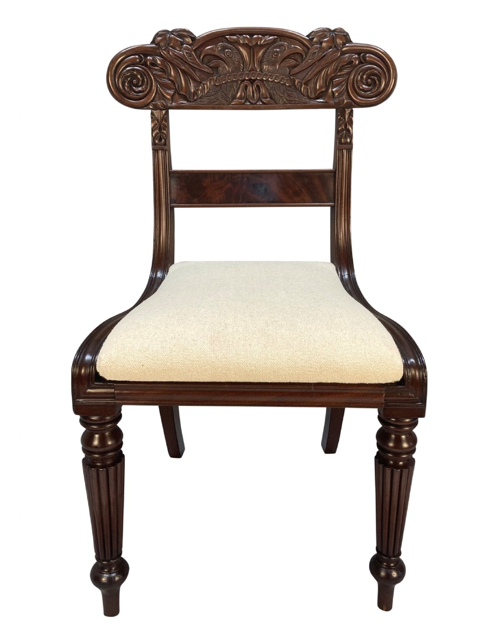 A set of four William IV Anglo-Indian dark wood dining chairs featuring carved scroll top rails, fluted turned front legs, and cream fabric seats. View II