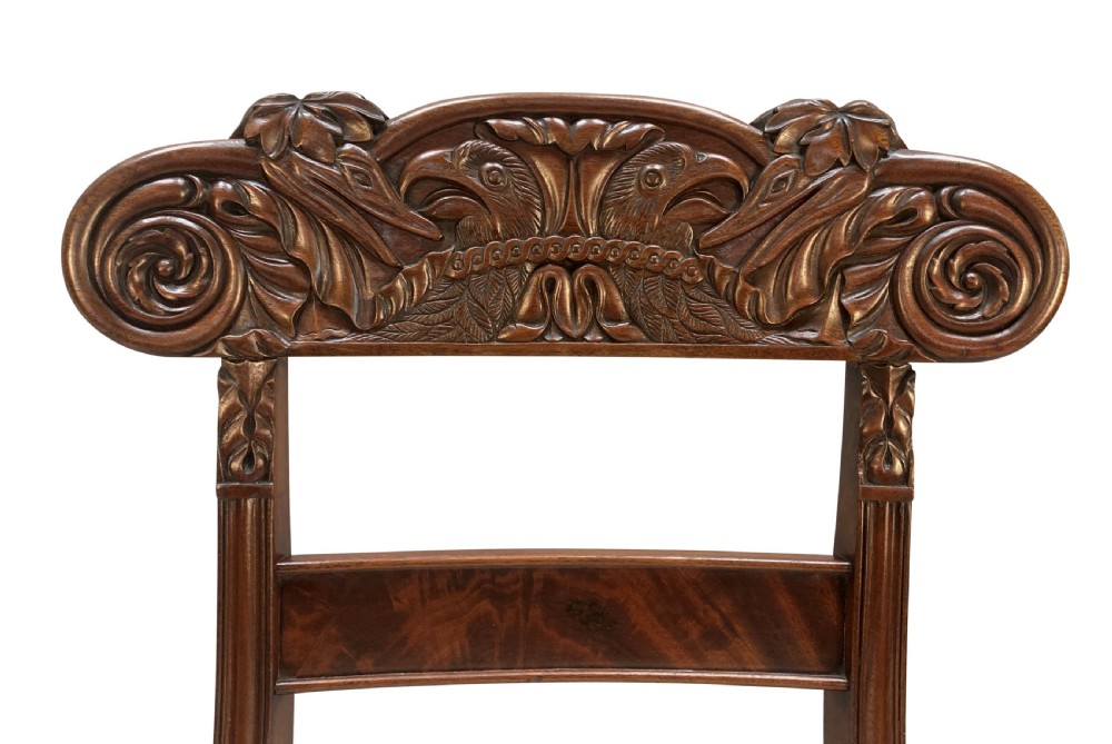 A set of four William IV Anglo-Indian dark wood dining chairs featuring carved scroll top rails, fluted turned front legs, and cream fabric seats. View VI
