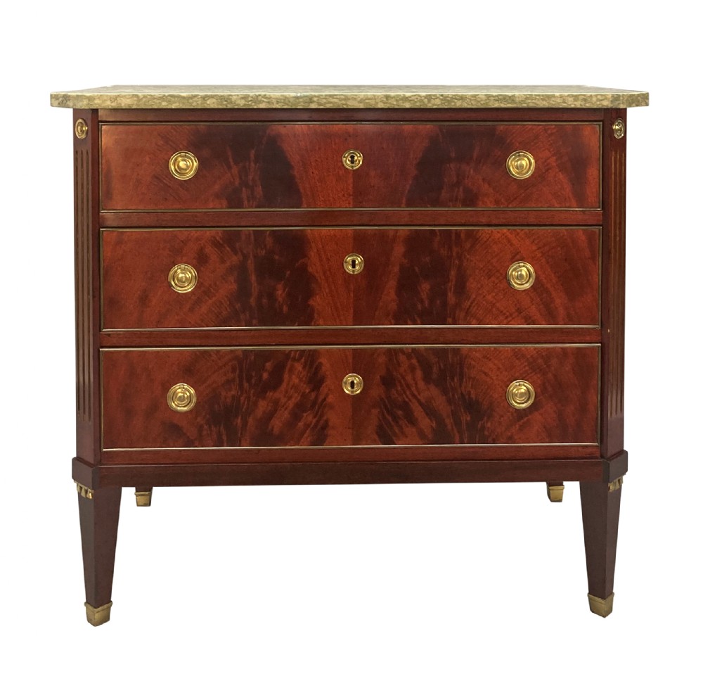 A 19th-century Russian flame mahogany commode featuring three drawers with brass ring handles, fluted corner pilasters, square tapered legs, and a pale green marble top.