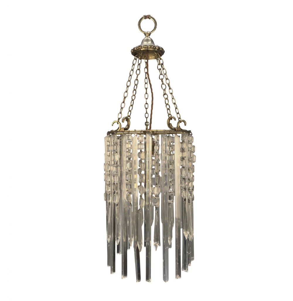 An antique cut glass waterfall pendant light featuring layered clear glass drops suspended from brass chains.